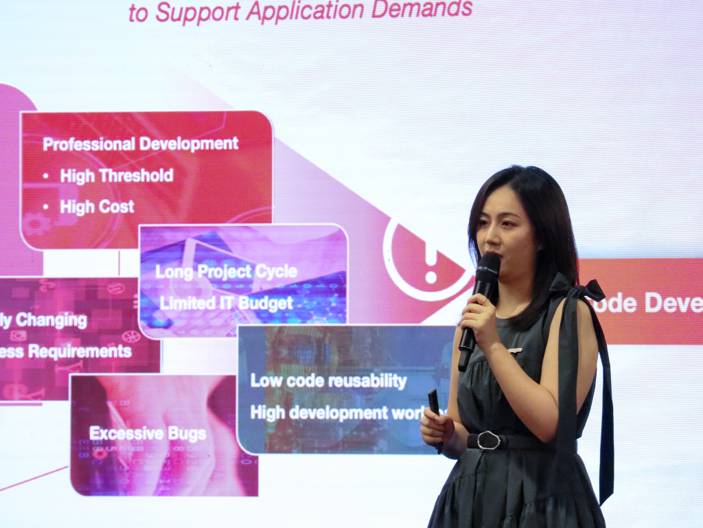 Phoebe Hu, Business Analyst at Yonyou Network Technology (Singapore), holding a microphone and speaking to the audience, with a PowerPoint presentation displayed behind her.