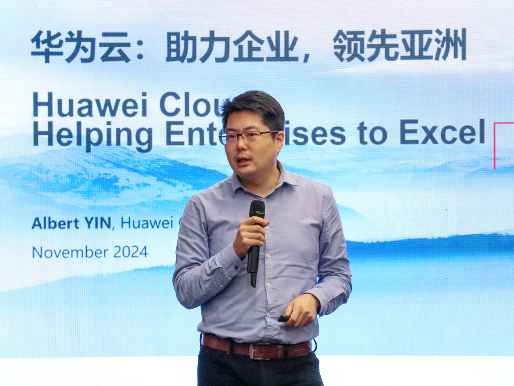 Albert Yin, Senior Cloud Account Manager of Huawei Cloud Singapore, holding a microphone while presenting the capabilities of Huawei Cloud Stack in enabling seamless cloud and on-premise deployment of Yonyou's enterprise systems, with a presentation slide in the background.