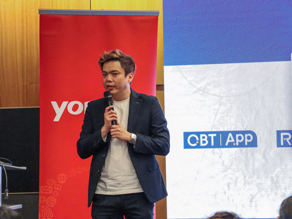 Jeffrey Soh, Regional Sales Director of Trip.Biz, speaking about the integration of Trip.Biz with Yonyou’s Business Travel & Expense Management platform. The background features Yonyou's logo on the left with a pull-up banner, and a PowerPoint slide on the right.