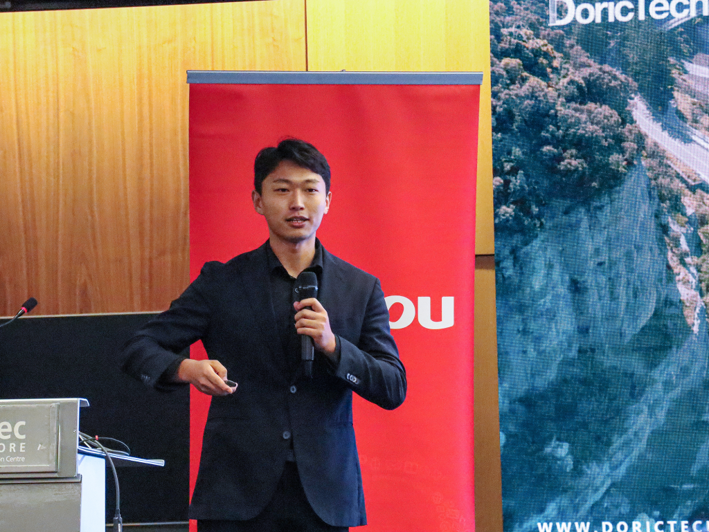 Tiago Fu, Sales Manager of DoricTech, presenting their suite of IoT and SaaS solutions designed. In the background, a banner with the Yonyou logo is visible.