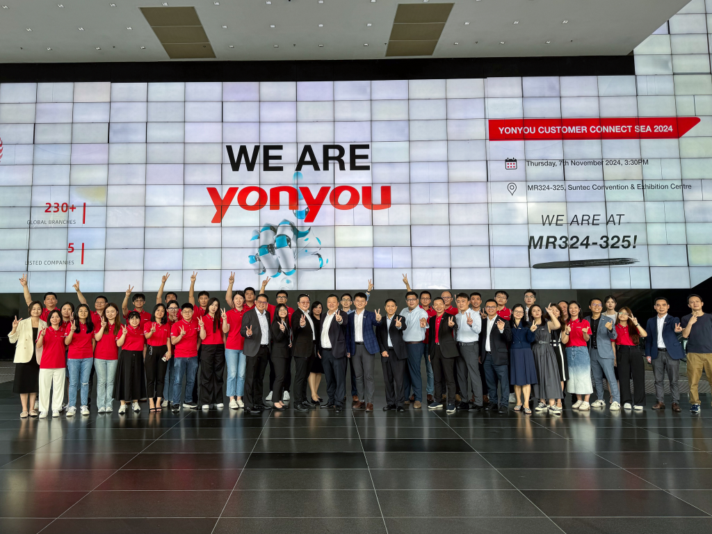 Group photo of attendees at the Yonyou Customer Connect SEA 2024 event, all smiling and making peace signs. The backdrop features a large screen displaying 'We are Yonyou' and the event title.